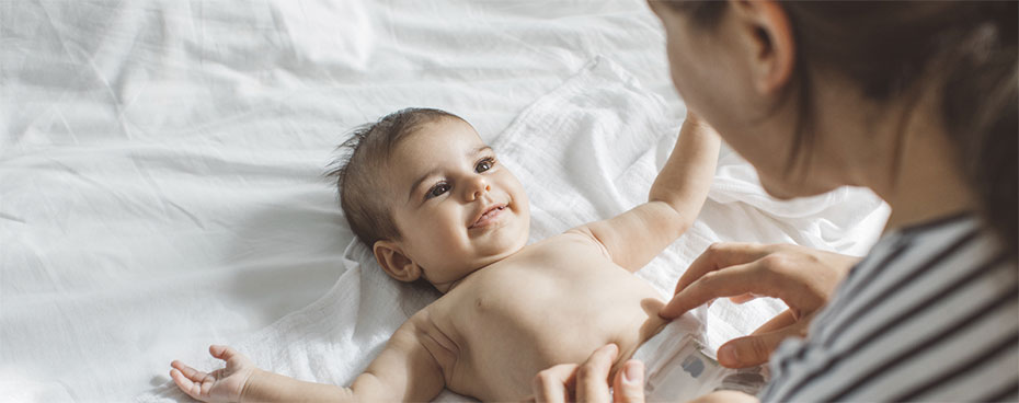 Vrouw verschoont baby op bed.