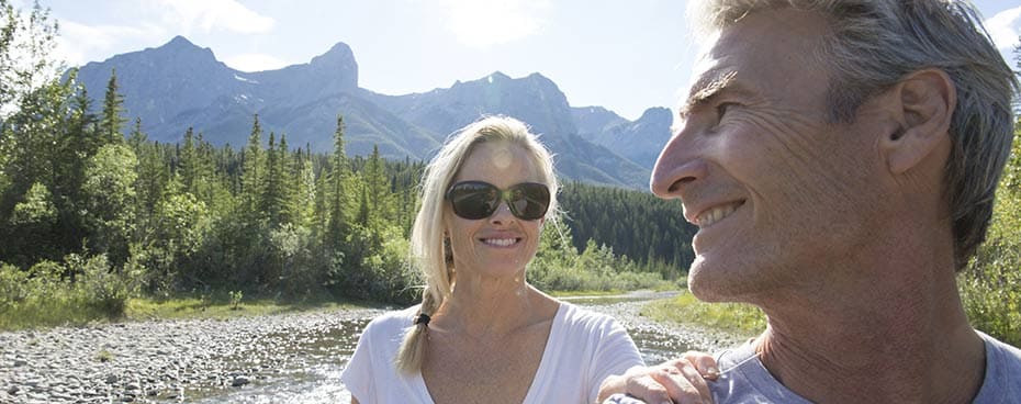 Vrolijke man en vrouw die wandelen door een bergachtig landschap.